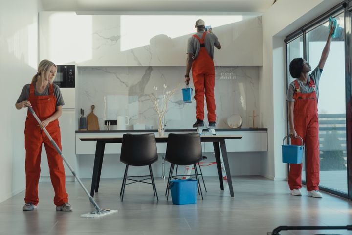 Uniformed commercial cleaning team mopping and wiping a modern premises