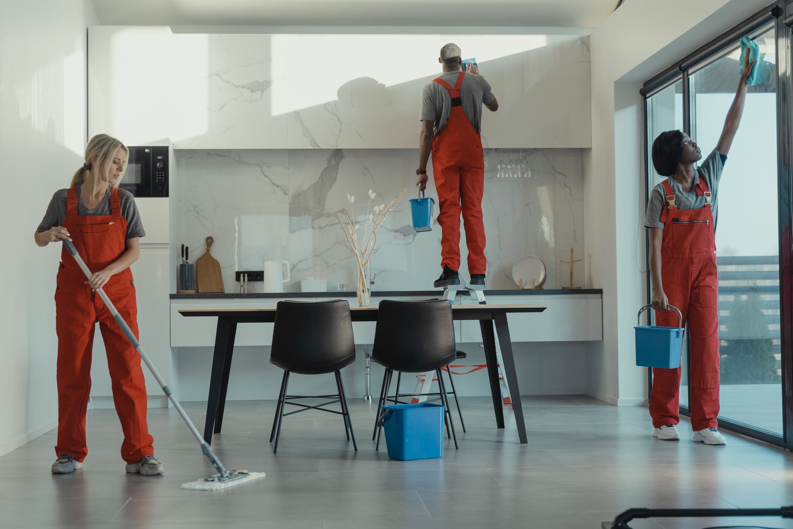 Uniformed commercial cleaning team mopping and wiping a modern premises
