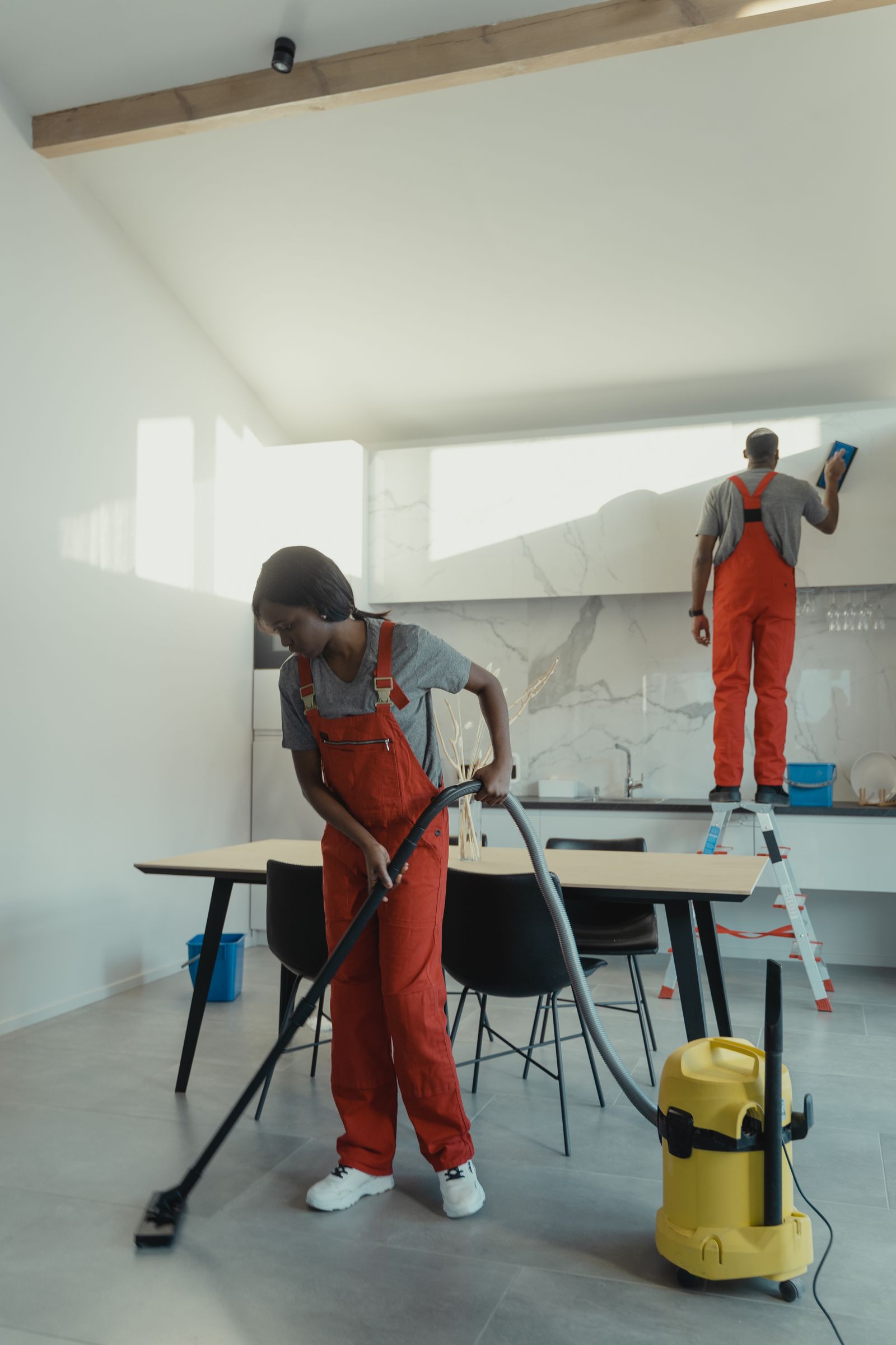 Professional cleaners deep cleaning a kitchen with equipment
