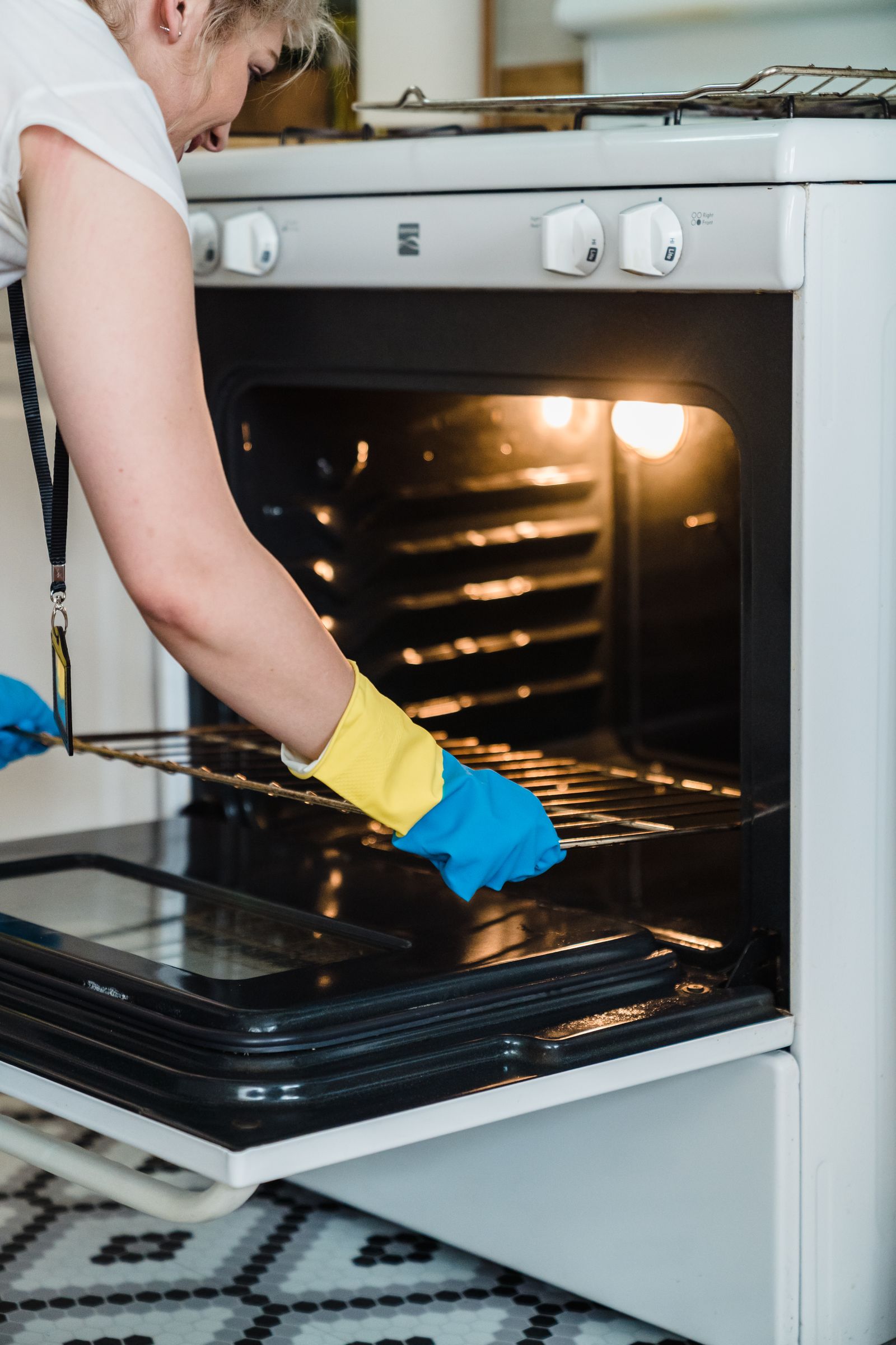 Gloved hand deep cleaning the inside of an oven