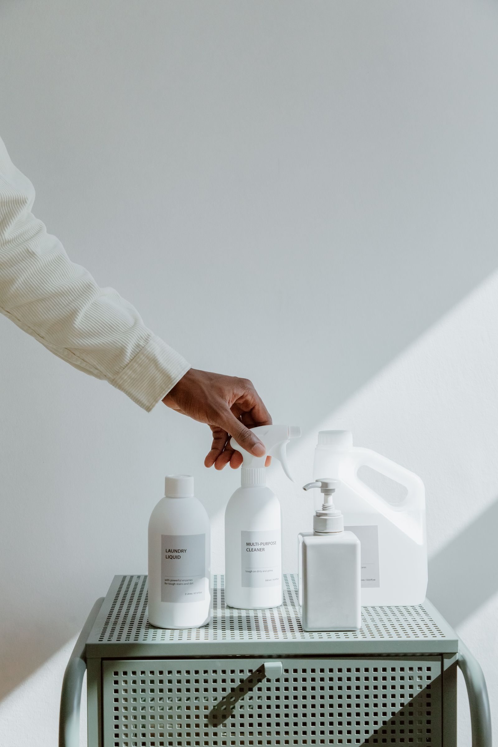 Hand reaching for eco-friendly cleaning products on a bright shelf