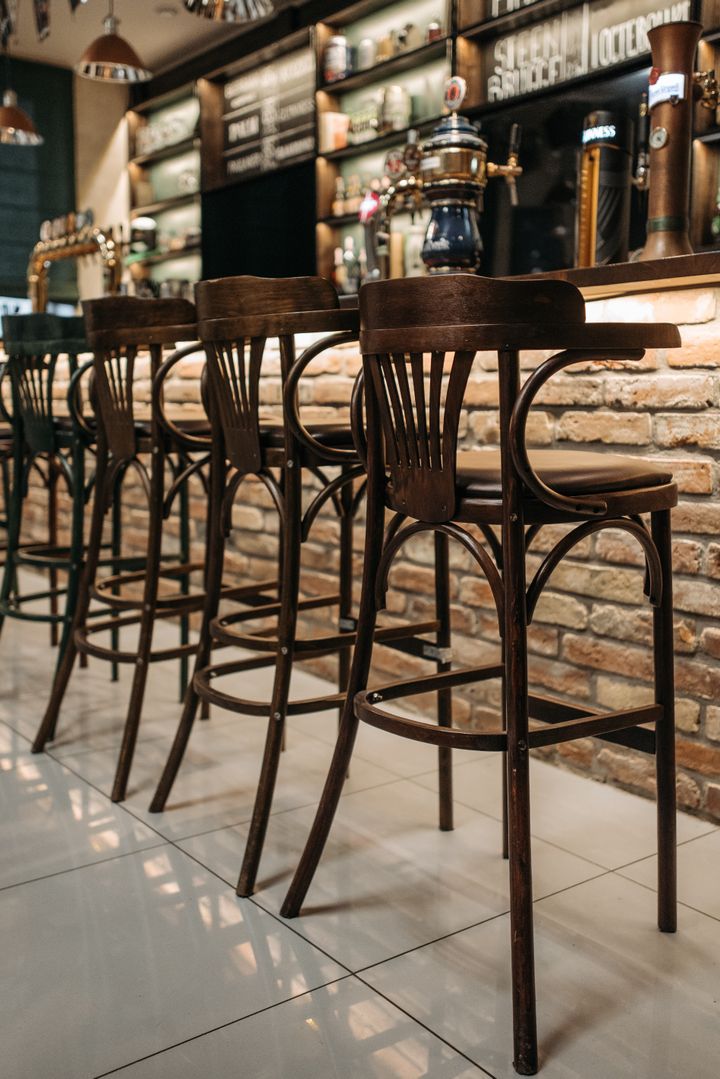 Clean wooden bar stools at a brick-fronted pub counter