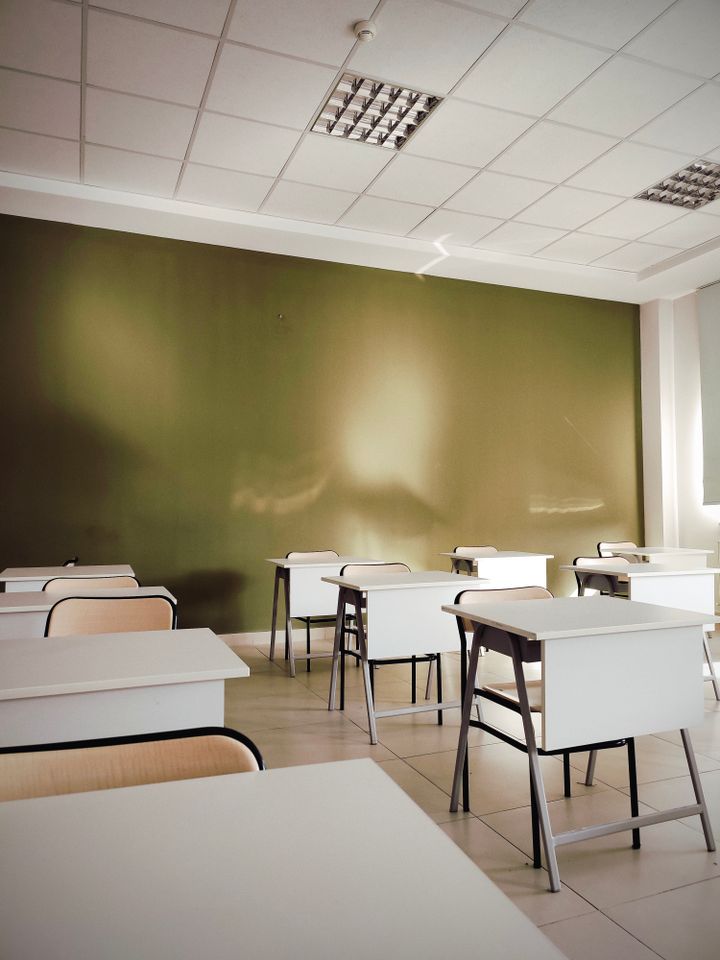 Bright, clean empty classroom with desks and a green board