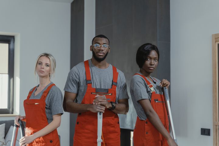 Three uniformed cleaners with mops and vacuum in a modern home